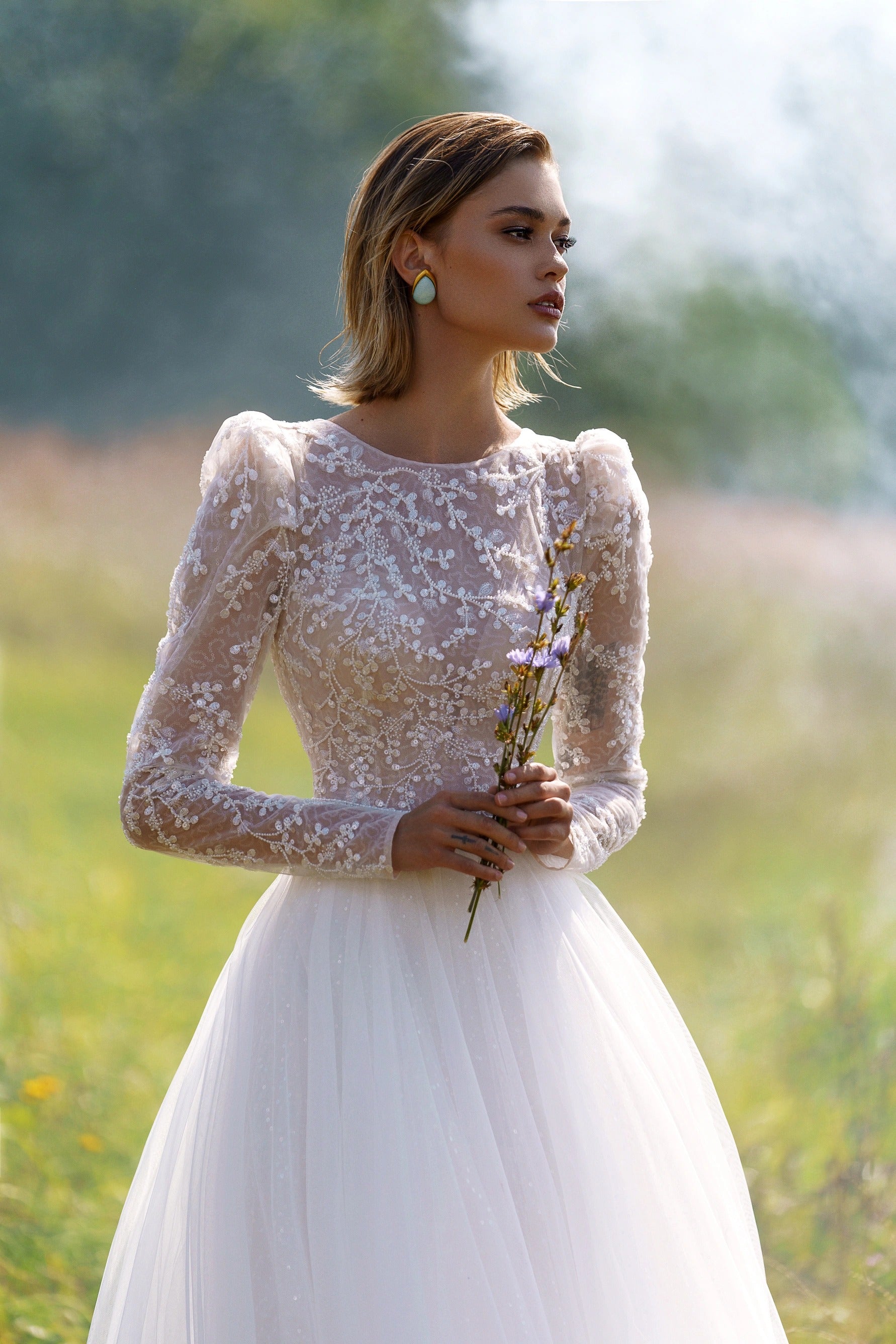 A-line wedding dress with long sleeves and closed back. The top is embroidered with lace.